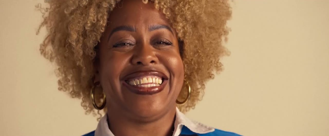 A woman with curly blond hair laughing toward the camera